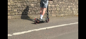 Picture of someone riding an E scooter on the pavement