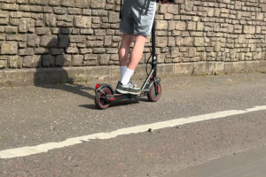 Picture of someone riding an E scooter on the pavement